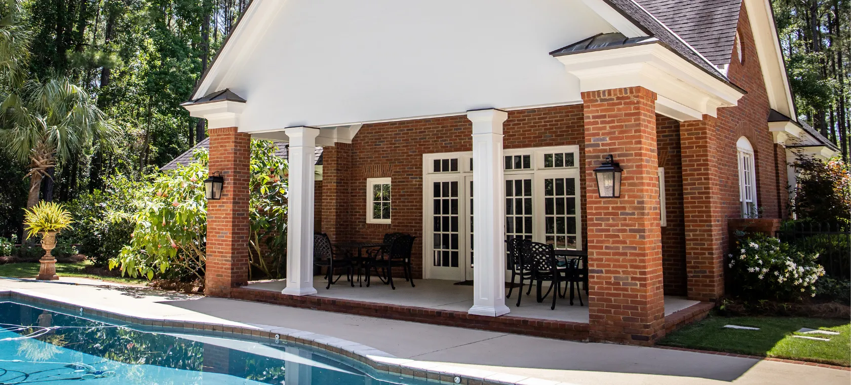 After pool house ADU Dallas TX project showing luxury backyard poolside suite with covered patio brick columns and private guest living space